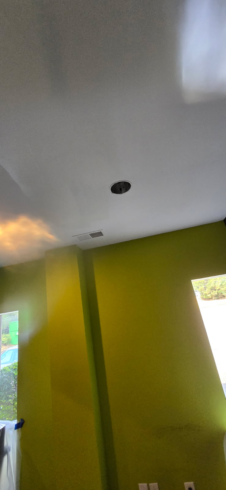 Ceiling with recessed lighting, green walls, windows.
