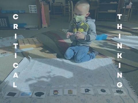 A young boy wearing a mask is kneeling on the floor playing with cards.