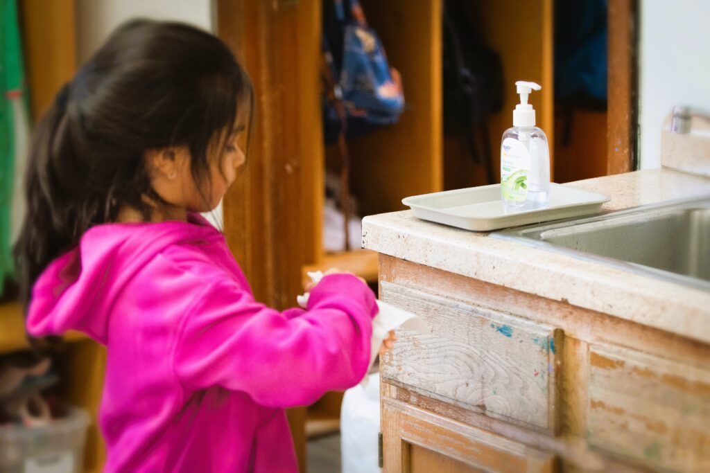 A little girl is washing her hands in a sink.