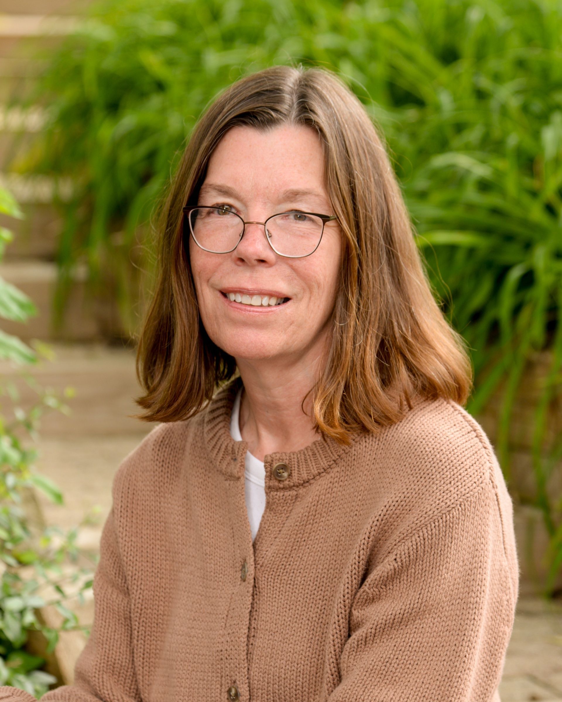 A woman is smiling in a circle with trees in the background