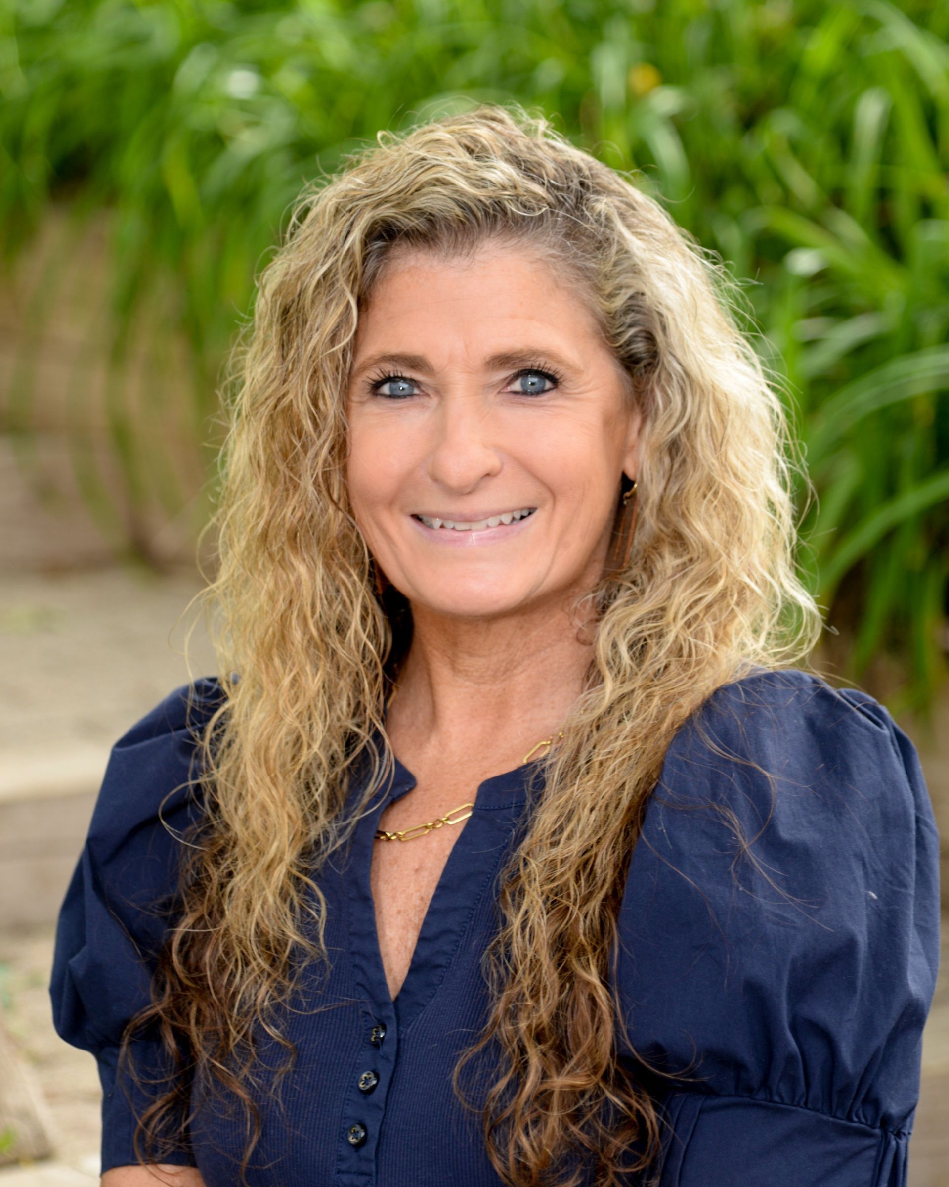 A woman with long curly hair is smiling in a circle.