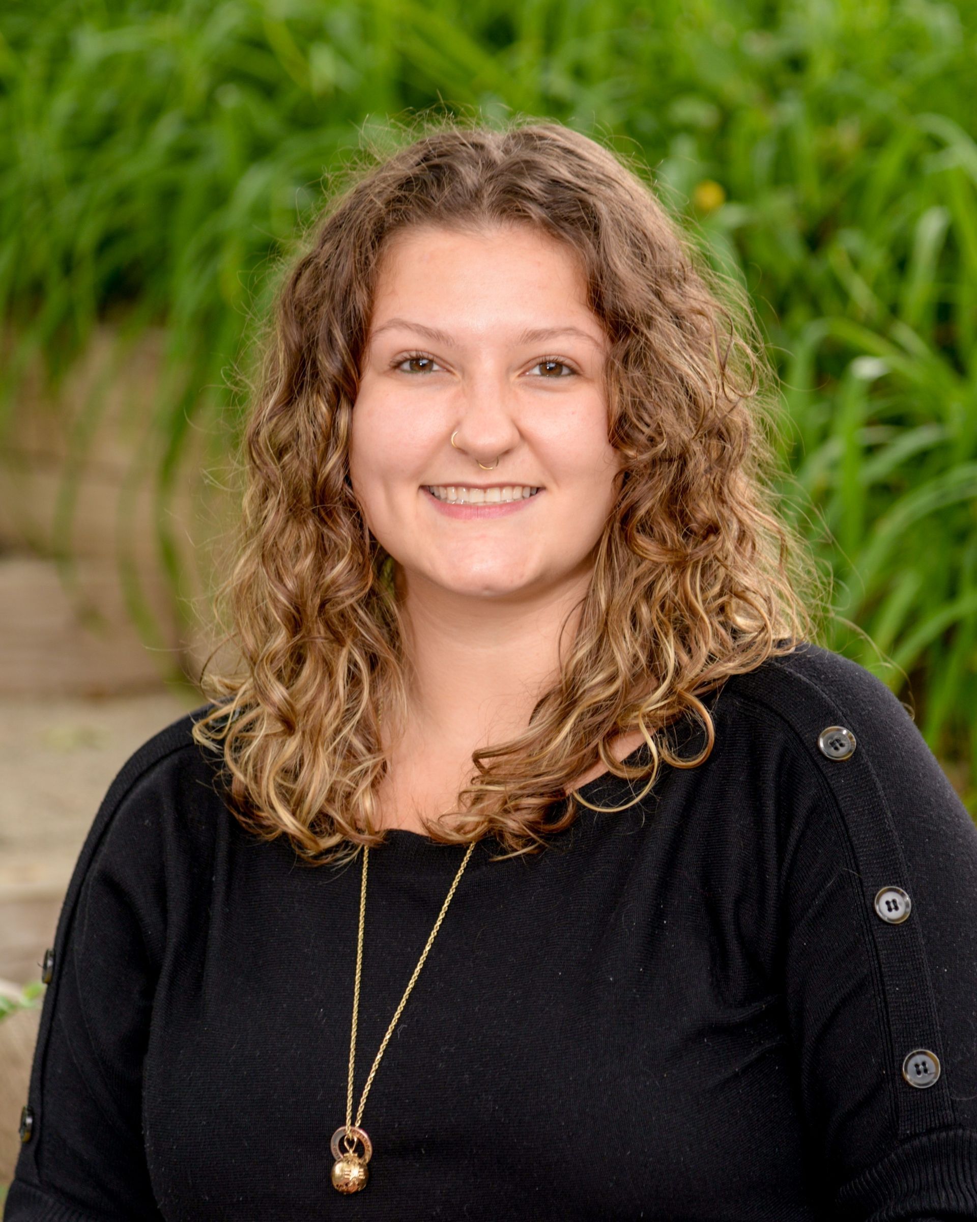 A woman with curly hair is smiling in a circle.
