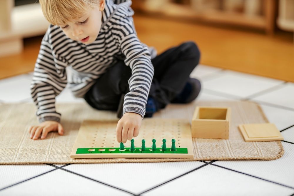 Child playing with a wooden counting toy on a rug in a bright room