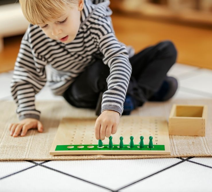 Child playing with a wooden counting toy on a rug in a bright room