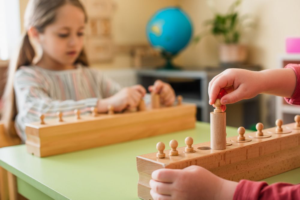 Children using wooden counting boards in a classroom, with a globe in the background