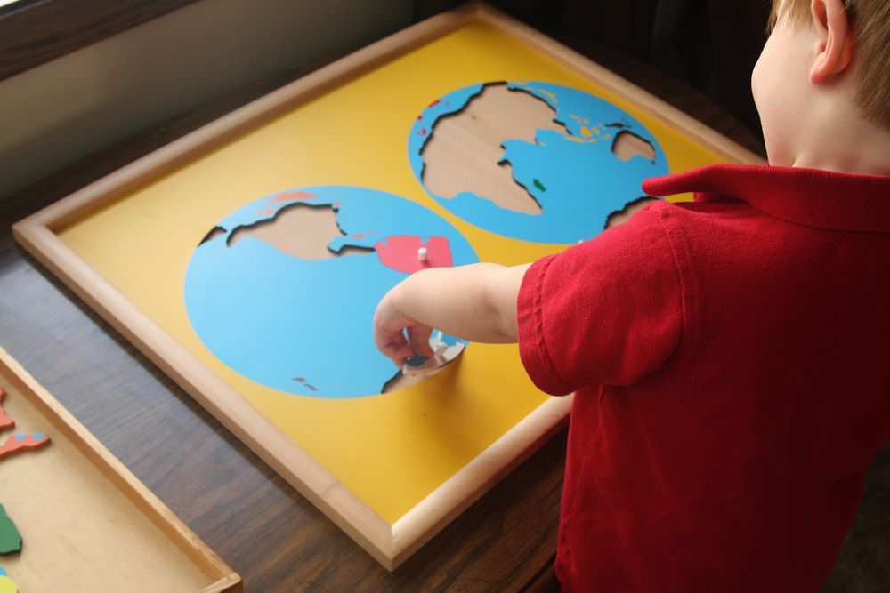 Montessori school toddler working with a geographical map as part of social studies curriculum.
