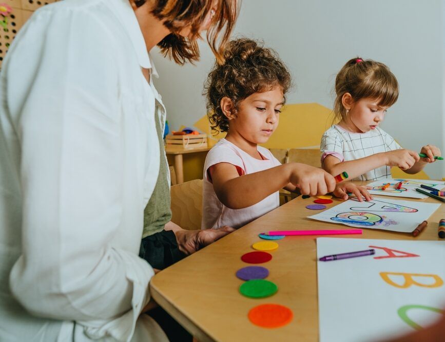 A woman is sitting at a table with two little girls.