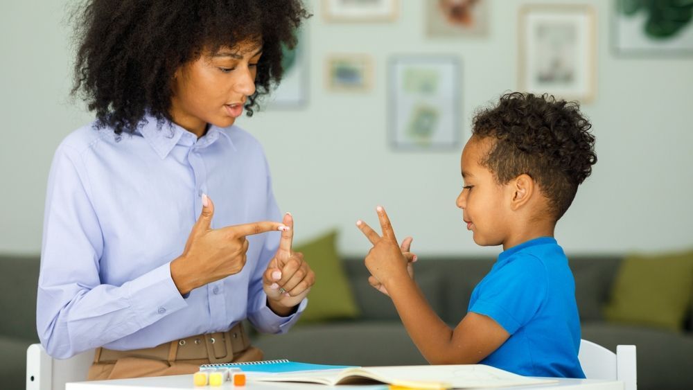 An African-American woman teaching a young African-American boy montessori math.