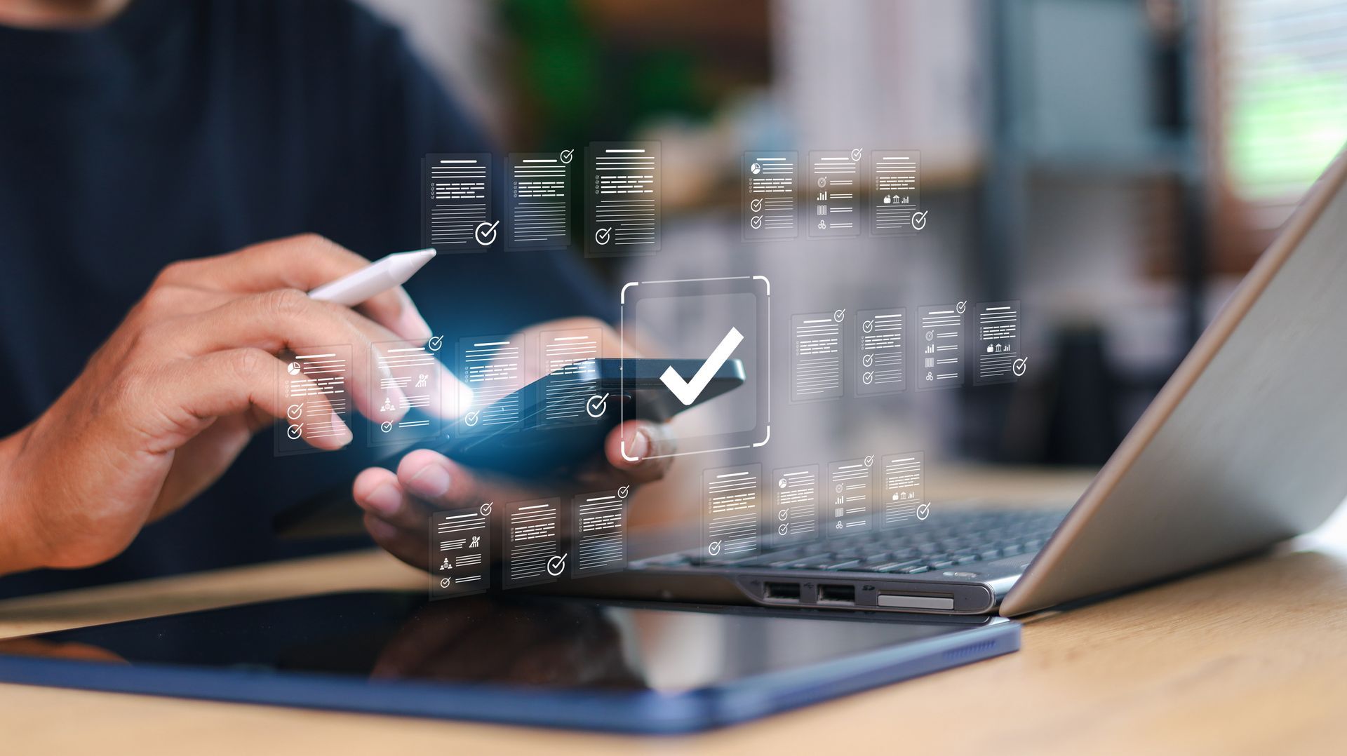 Person using a phone with a digital check mark over it, near a laptop and tablet.