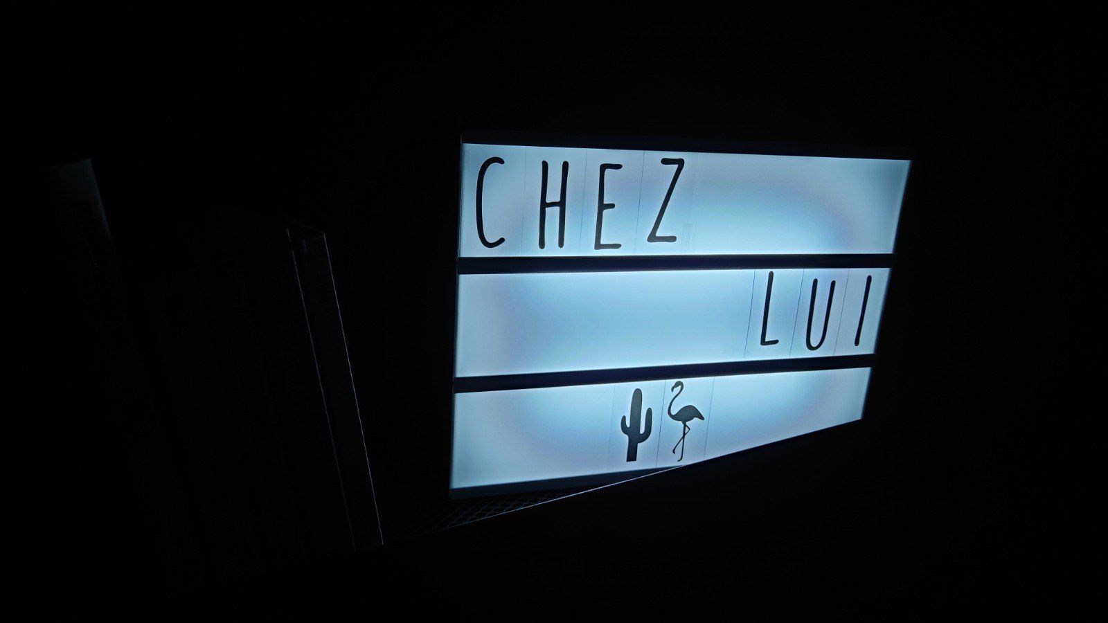 Enseigne rétroéclairée portant l'inscription « CHEZ LOU » avec un petit symbole de feuille de cannabis