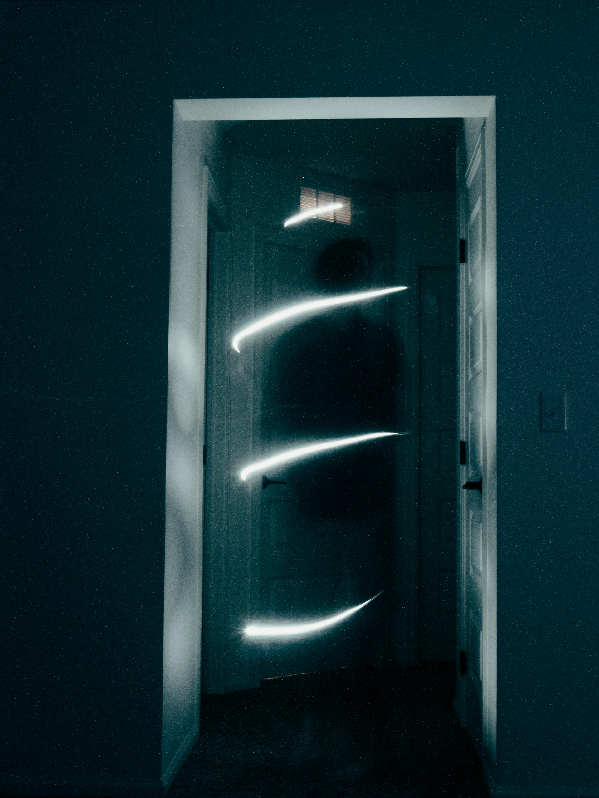 Une entrée sombre avec une porte obscure reflétant à l'intérieur des traînées de lumière courbes et brillantes