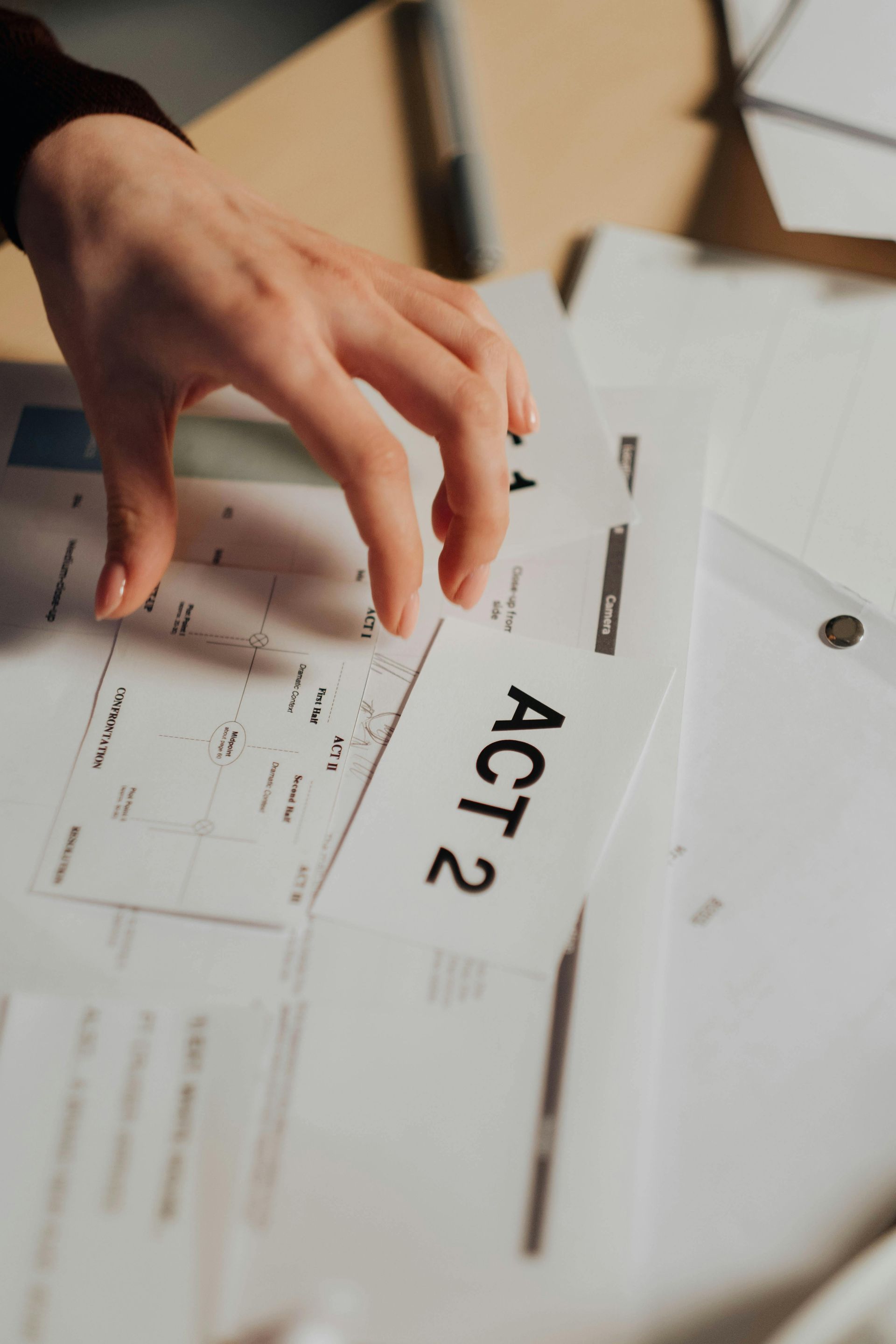 La main pose une carte ACT2 sur un bureau blanc où traînent des papiers et des enveloppes.