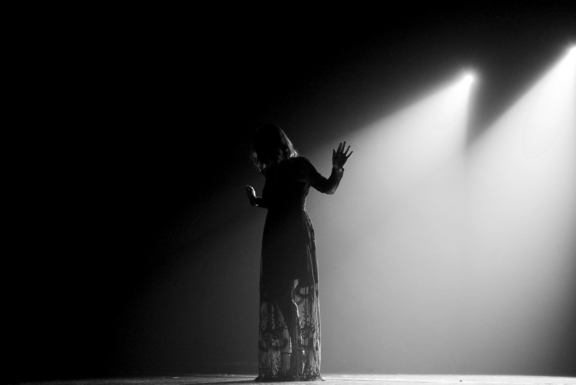 Artiste en silhouette sous deux projecteurs puissants sur une scène obscure