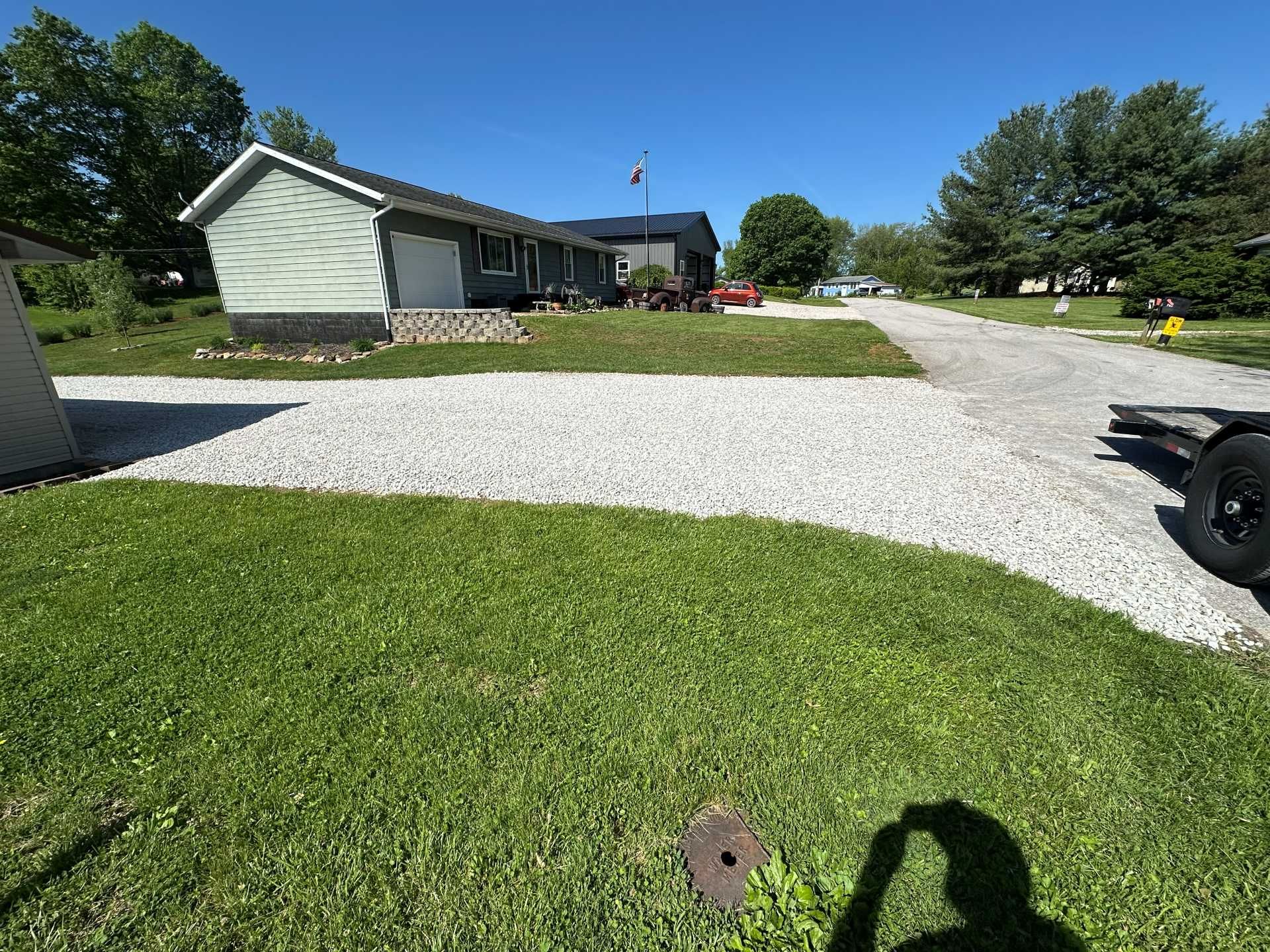 A light-colored house with a gravel driveway set against a clear blue sky on a sunny day.