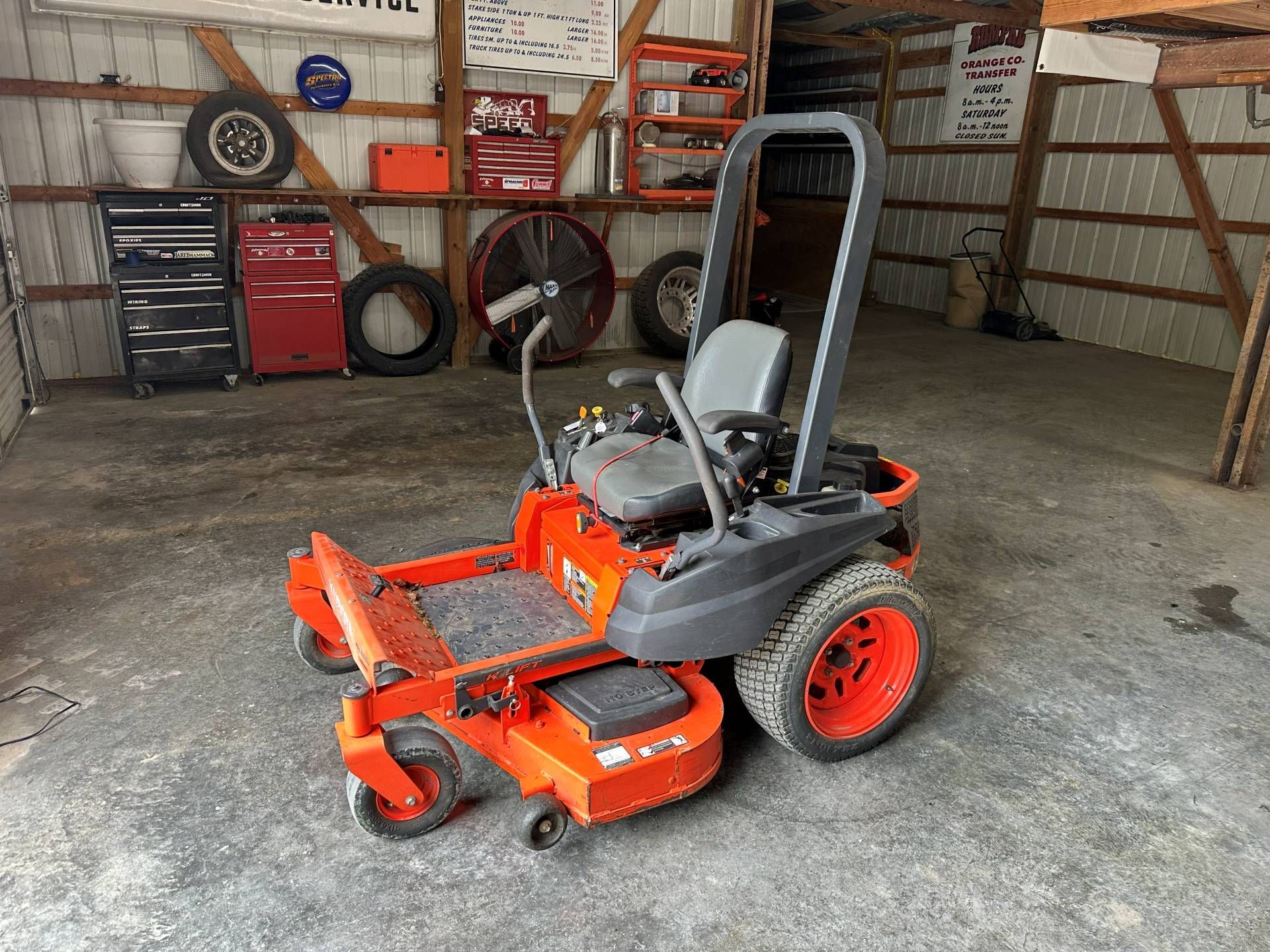 An orange Kubota zero-turn lawn mower parked on a concrete floor inside a garage.