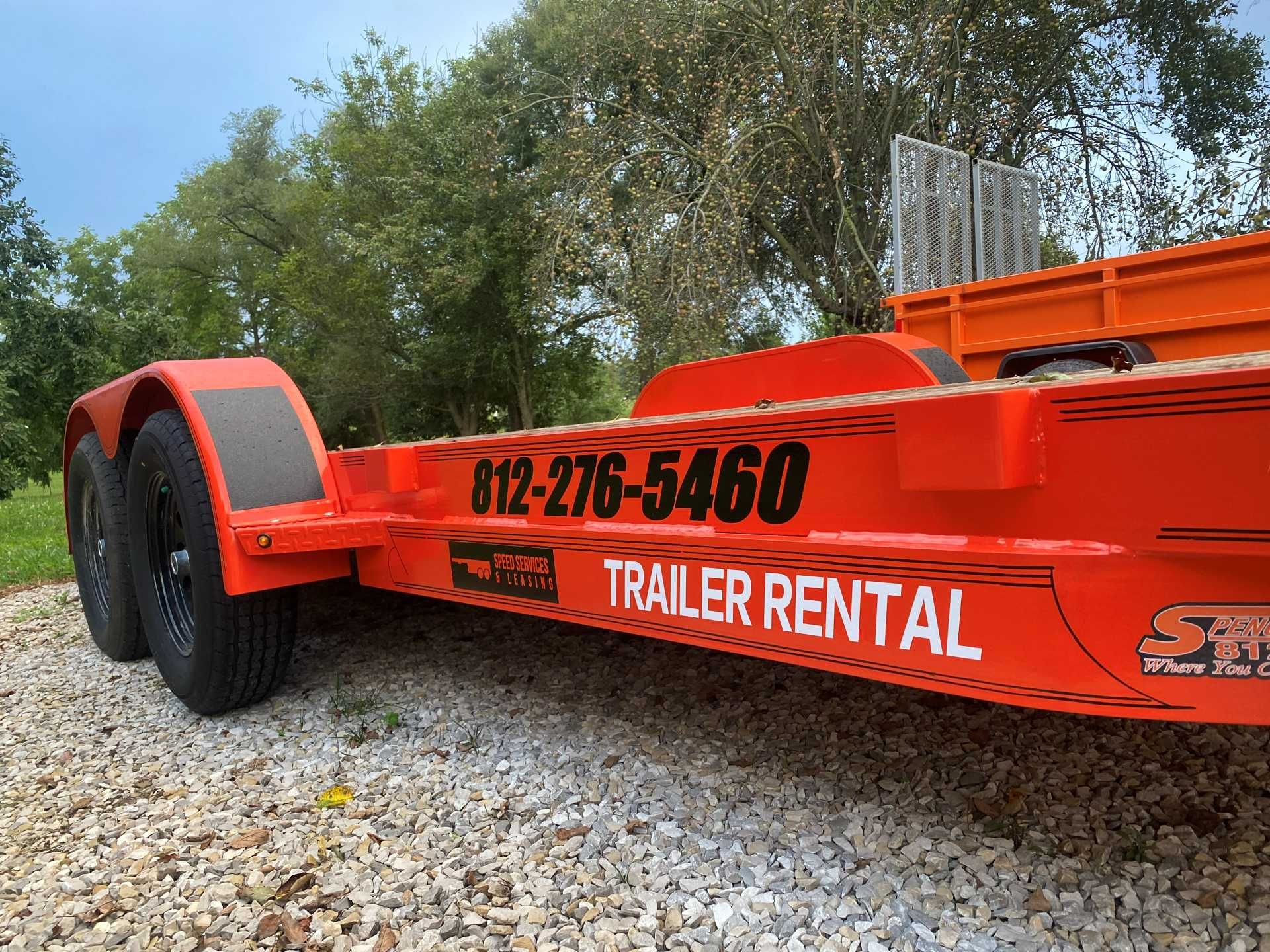 Bright orange trailer parked on a gravel surface with the phone number 812-276-5460 and text 
