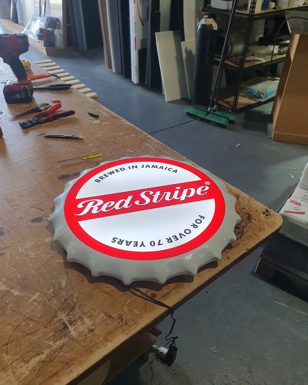 A Red Stripe Bottle Cap is Sitting on a Wooden Table — Coastal Plastics In Tweed Heads South, NSW