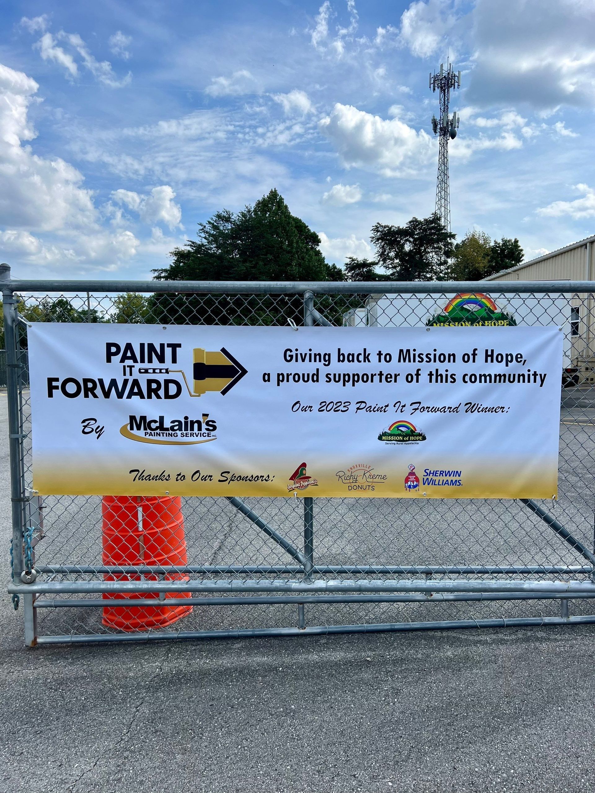 A sign on a fence says paint it forward.