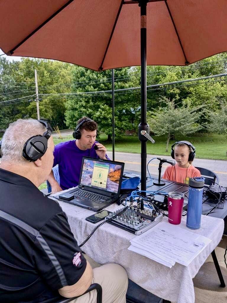 A group of people are sitting at a table under an umbrella.
