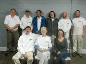 A group of people posing for a picture with one woman sitting in a chair