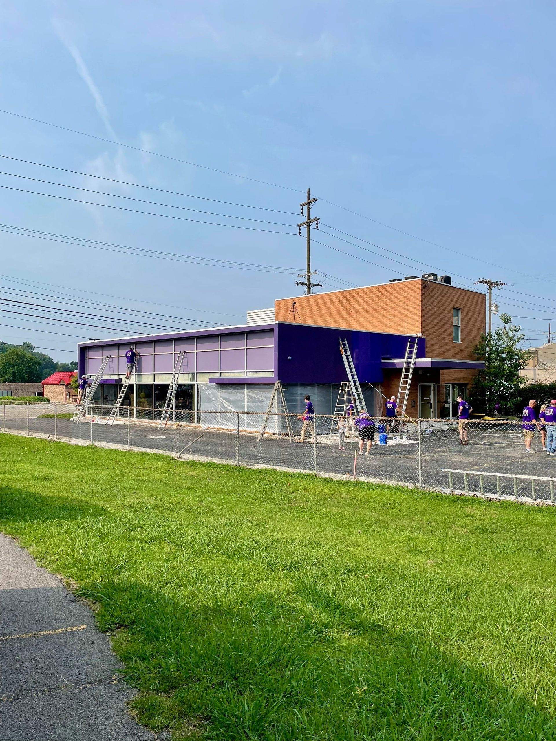 A group of people are painting a purple building.
