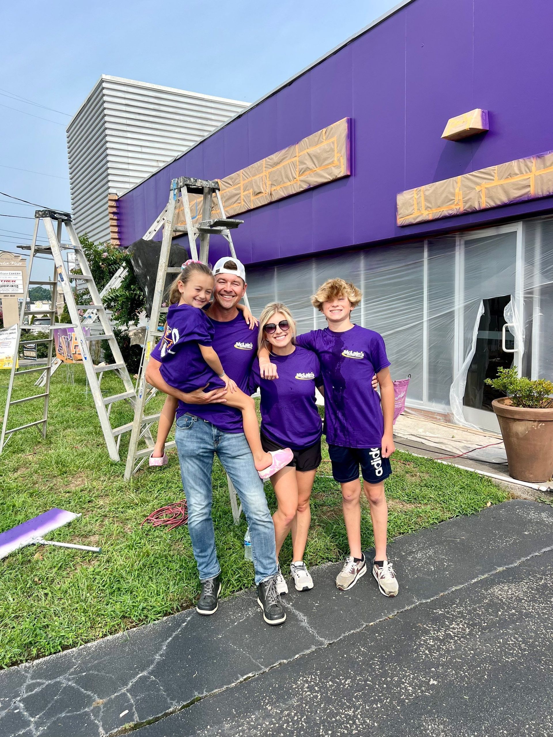 A family is standing in front of a purple building.