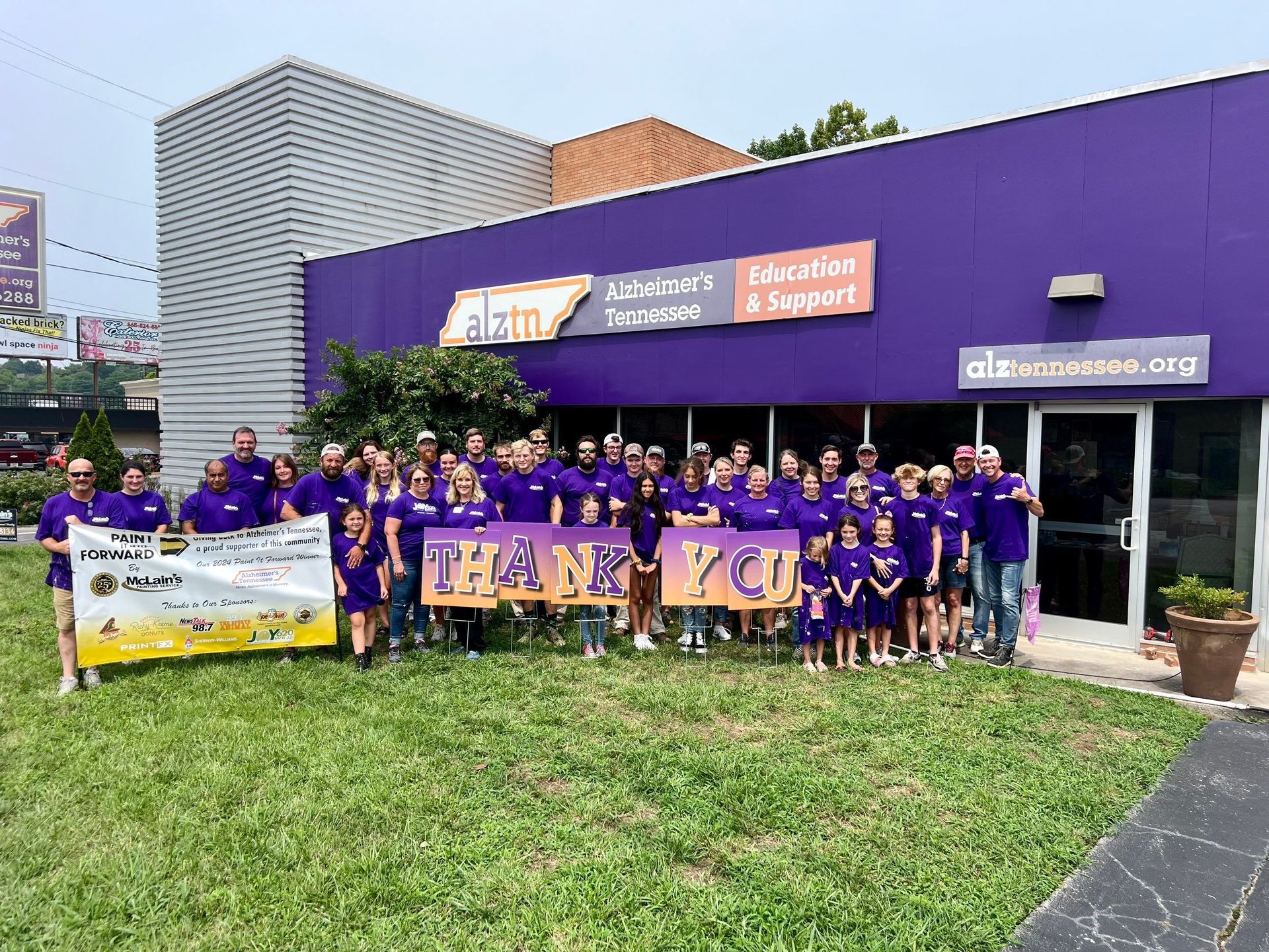 A group of people are posing for a picture in front of a purple building.