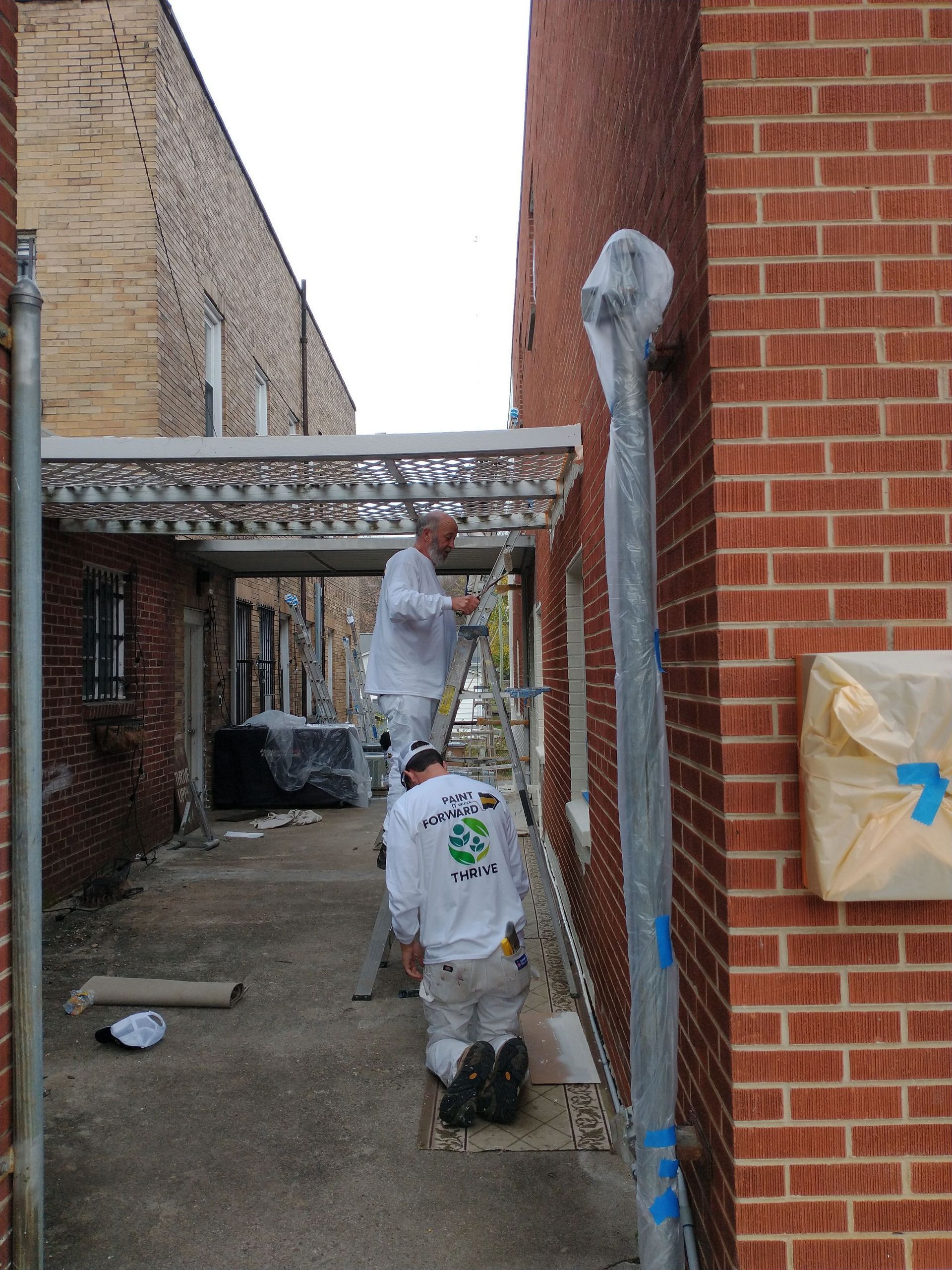 Two men are painting the side of a brick building