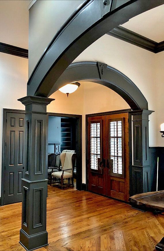 a hallway with a black archway and wooden floors