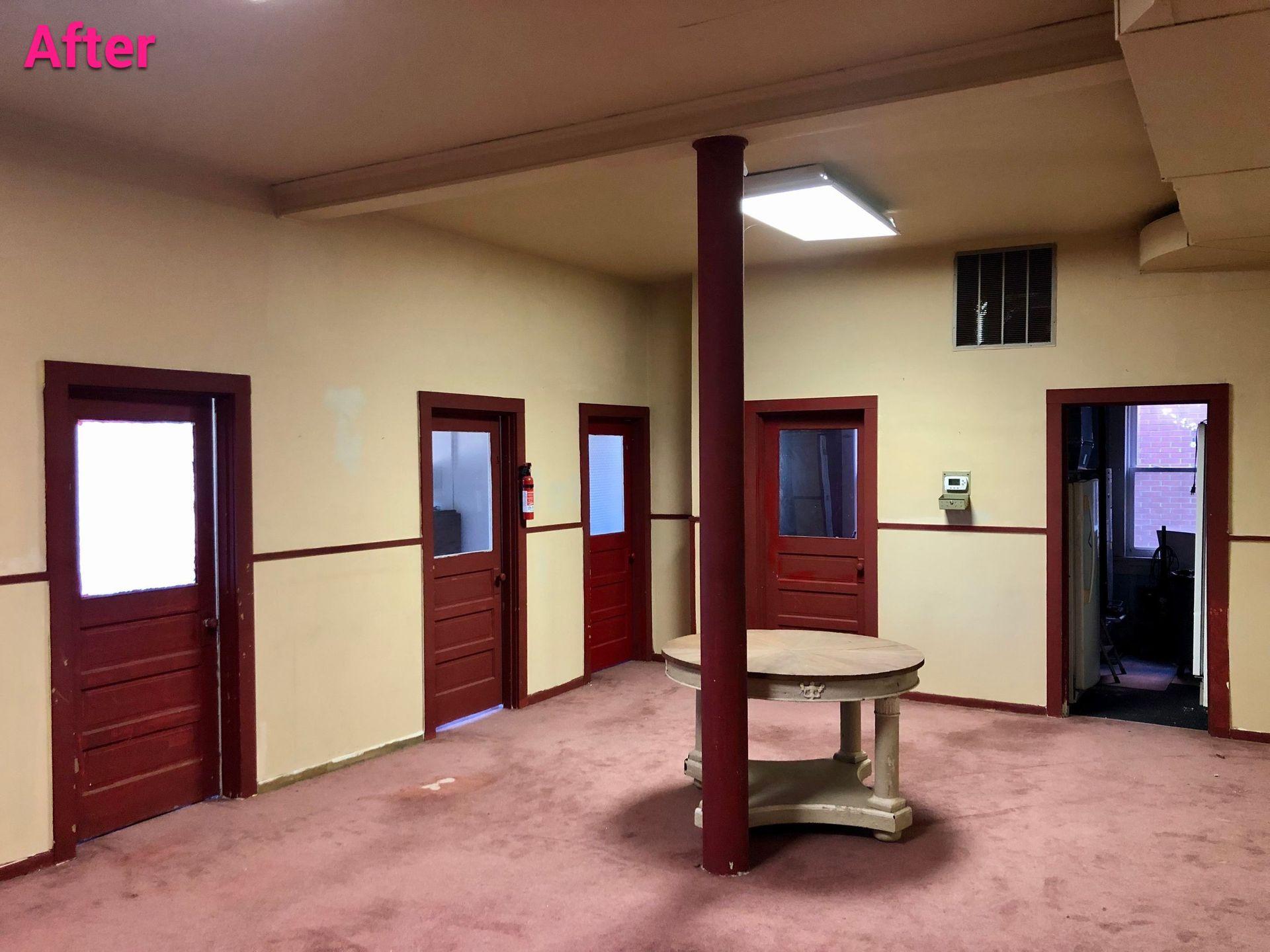 An empty room with red doors and a table in the middle
