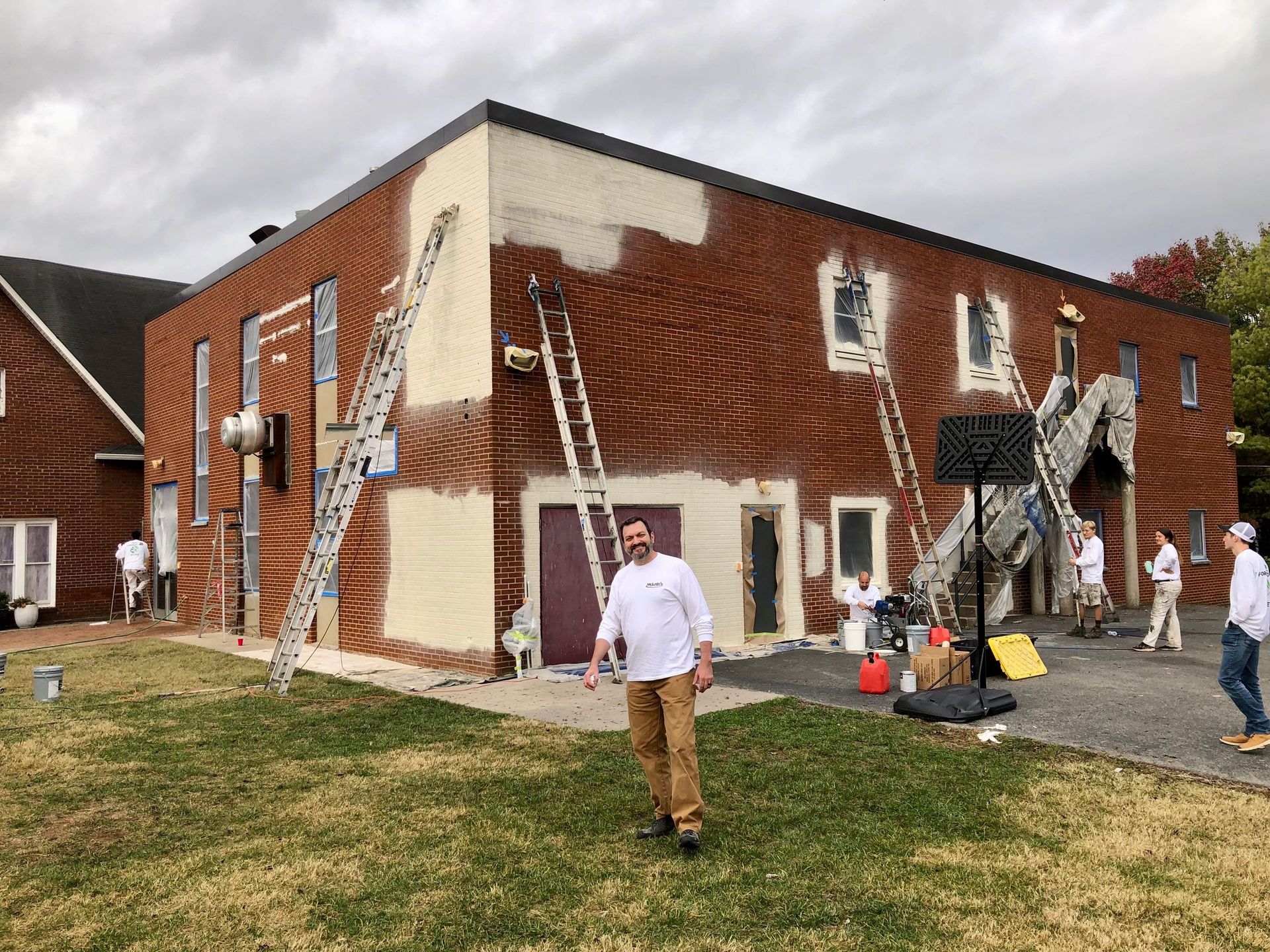 A man is standing in front of a building that is being painted.