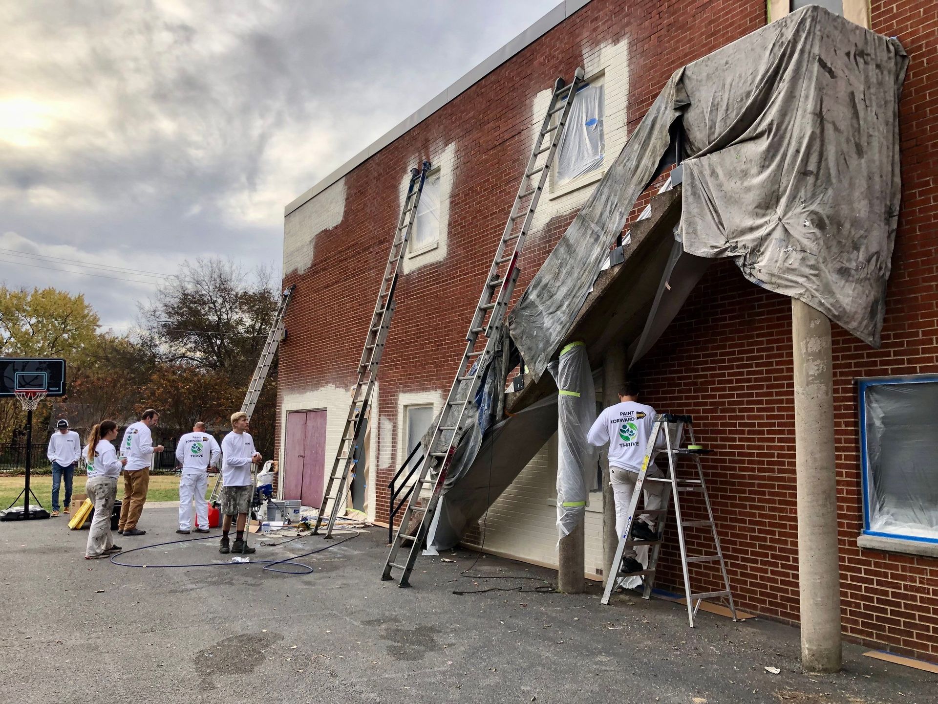 A group of people are painting a brick building.
