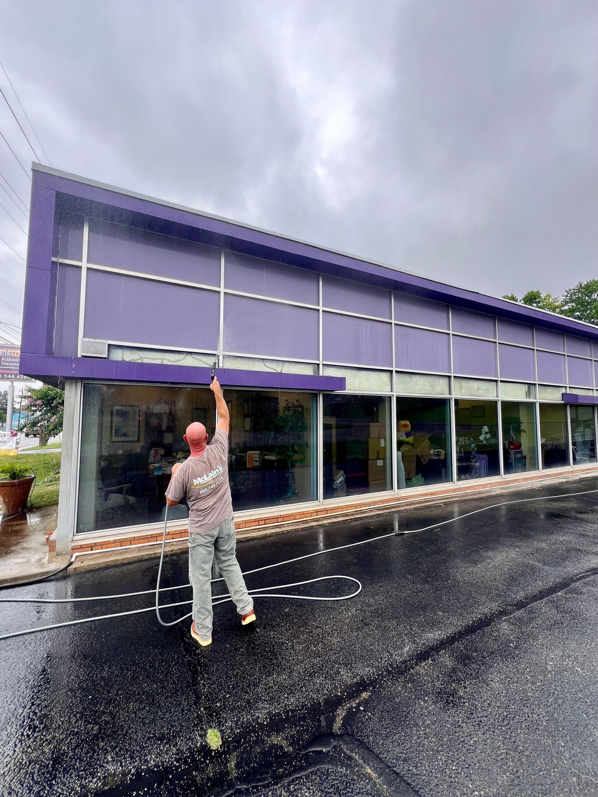 A man is cleaning the windows of a purple building.
