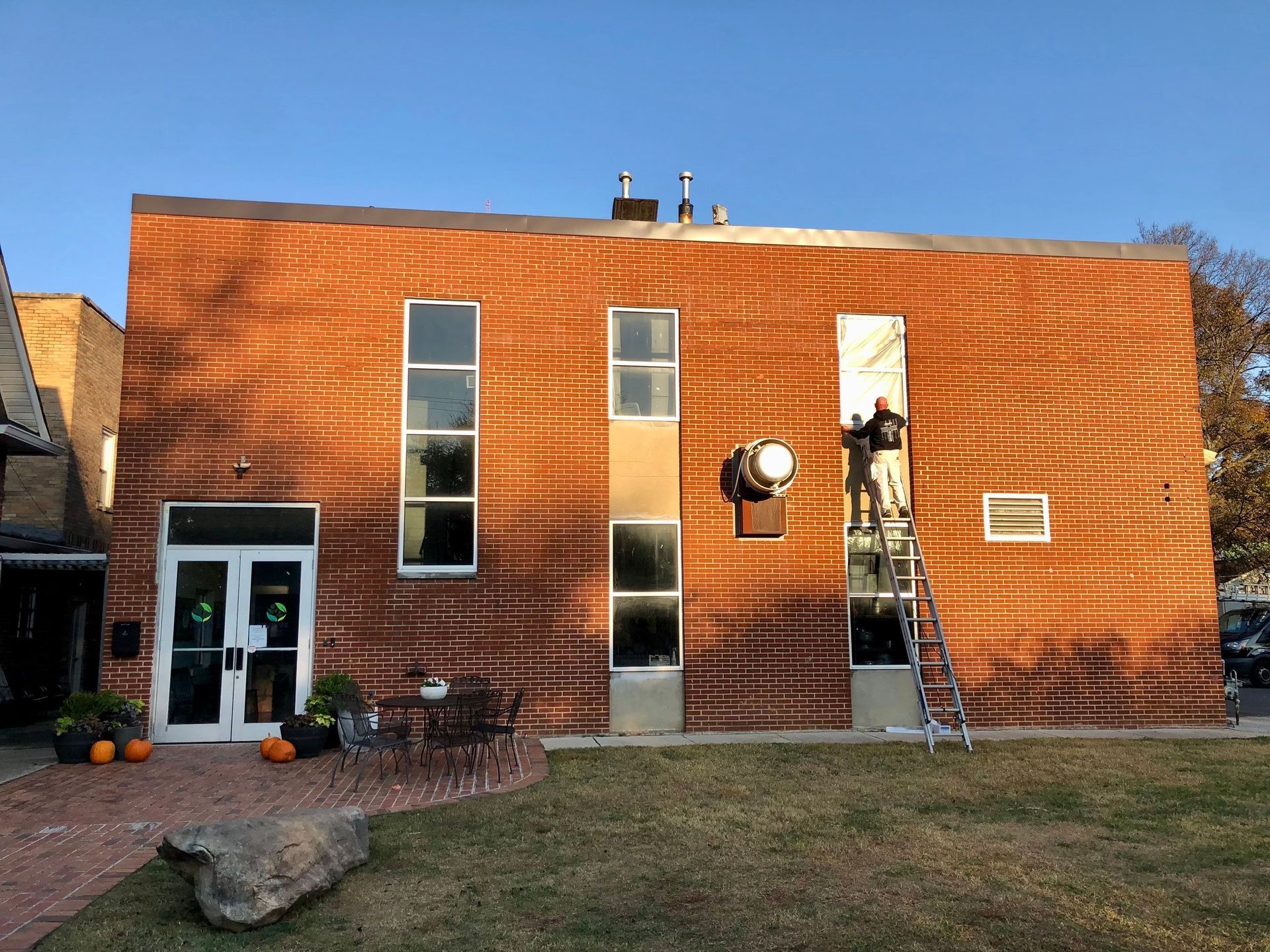 A brick building with a lot of windows and pumpkins in front of it.