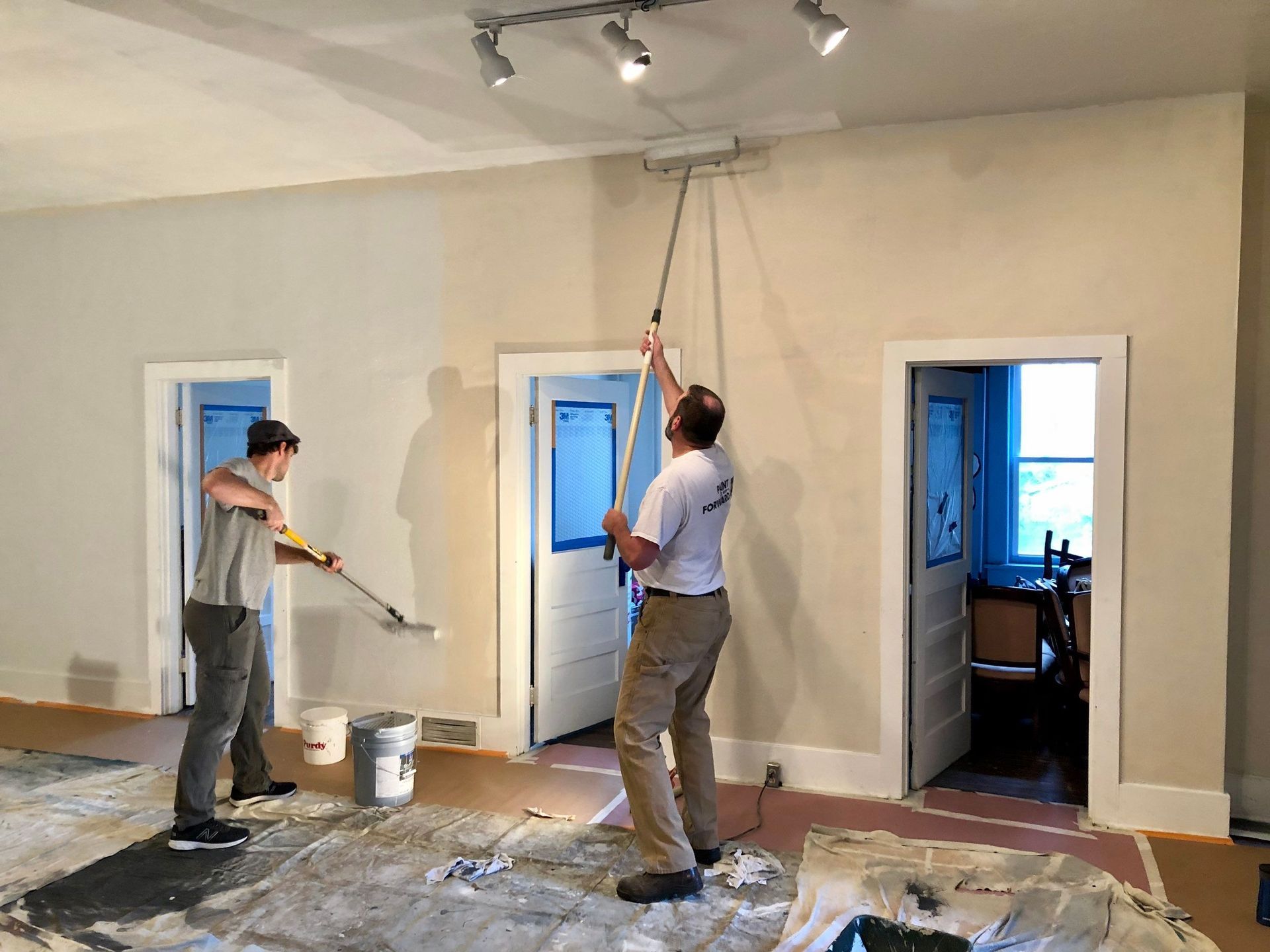 Two men are painting the walls of a house