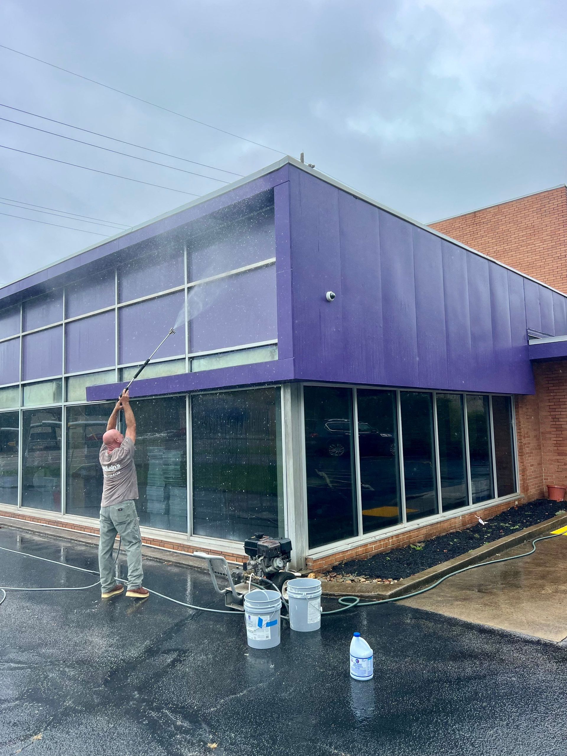A man is washing the windows of a purple building.