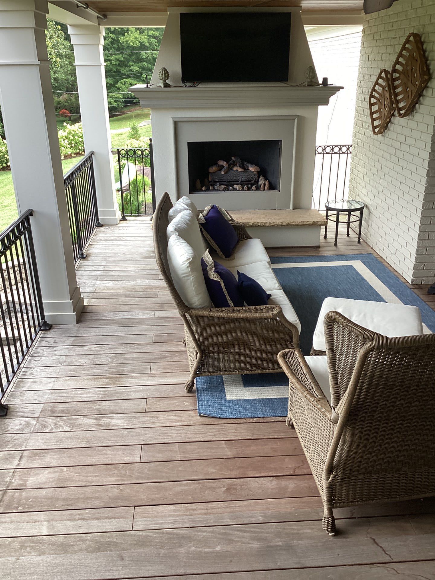 A porch with a couch , chairs , and a fireplace.