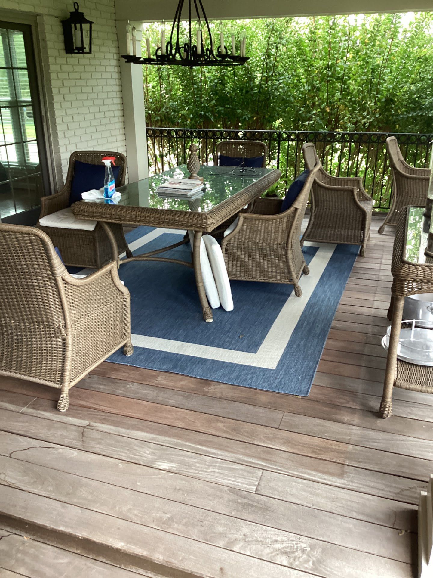There is a table and chairs on the porch with a blue rug.