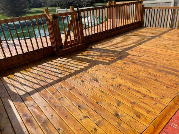 A wooden deck with a fence and a pool in the background.