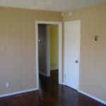 An empty room with hardwood floors and beige walls.