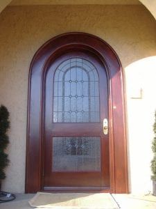 A large wooden door with a stained glass window