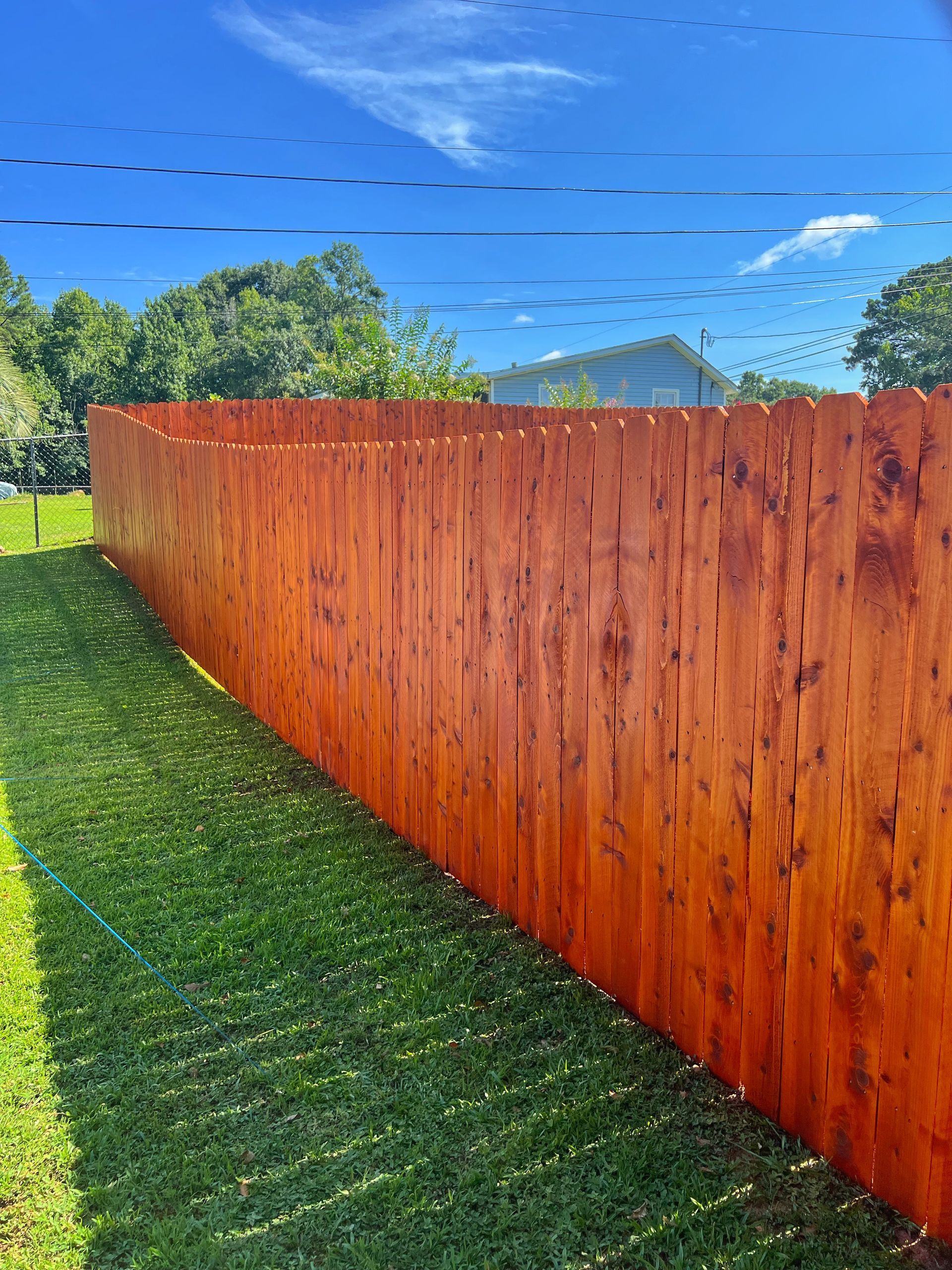 A long wooden fence is sitting in the middle of a lush green field.