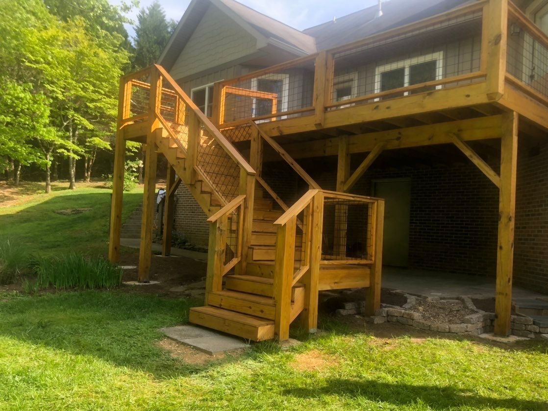A wooden deck with stairs leading up to it is in front of a house.