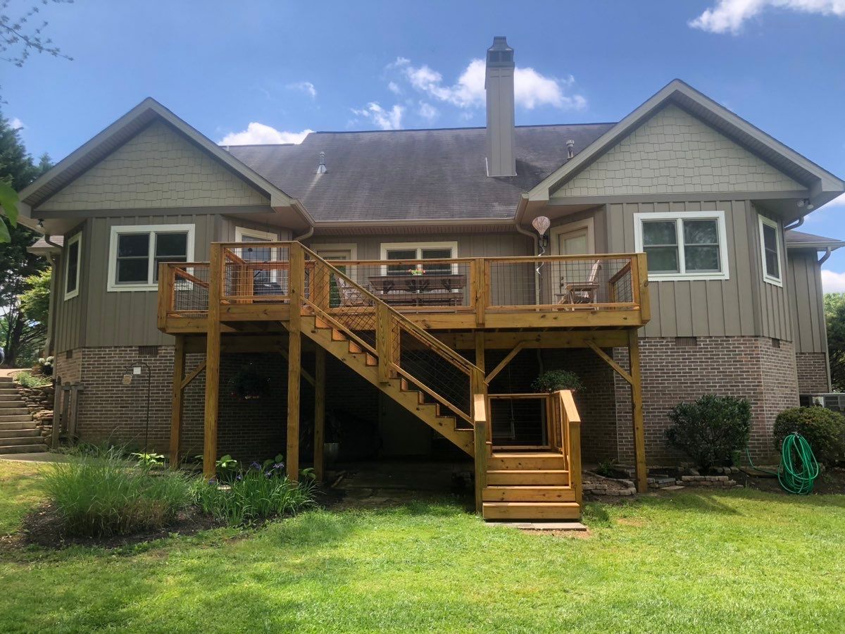 The back of a house with a wooden deck and stairs.