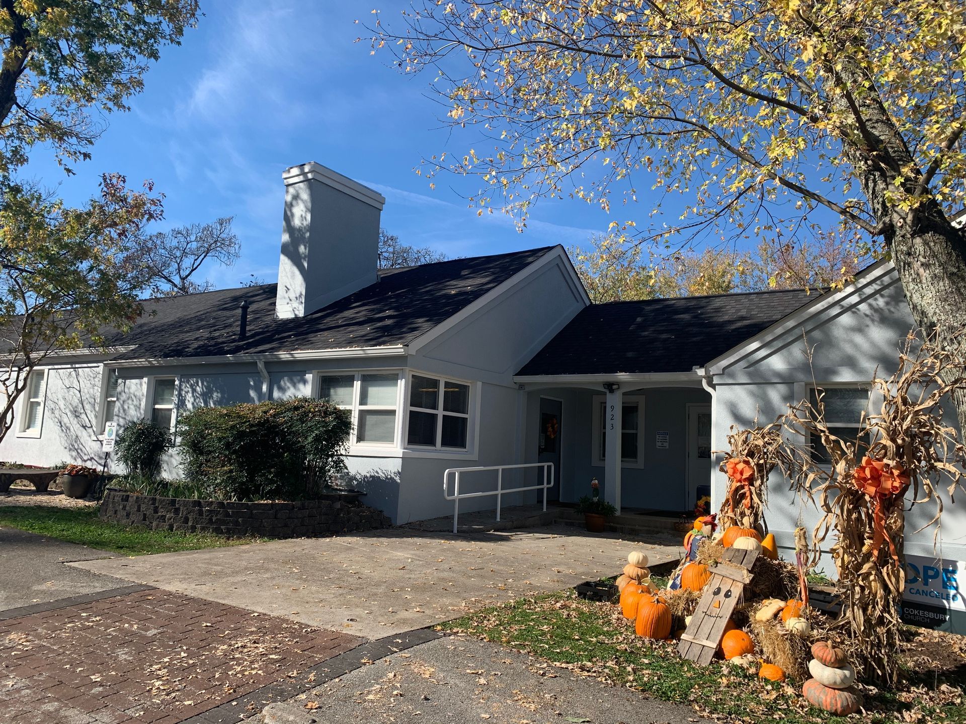 A white house with pumpkins in front of it on a sunny day
