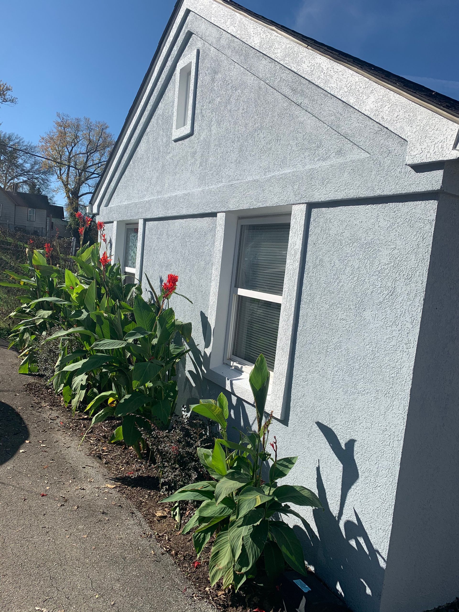 A white house with flowers in front of it on a sunny day.