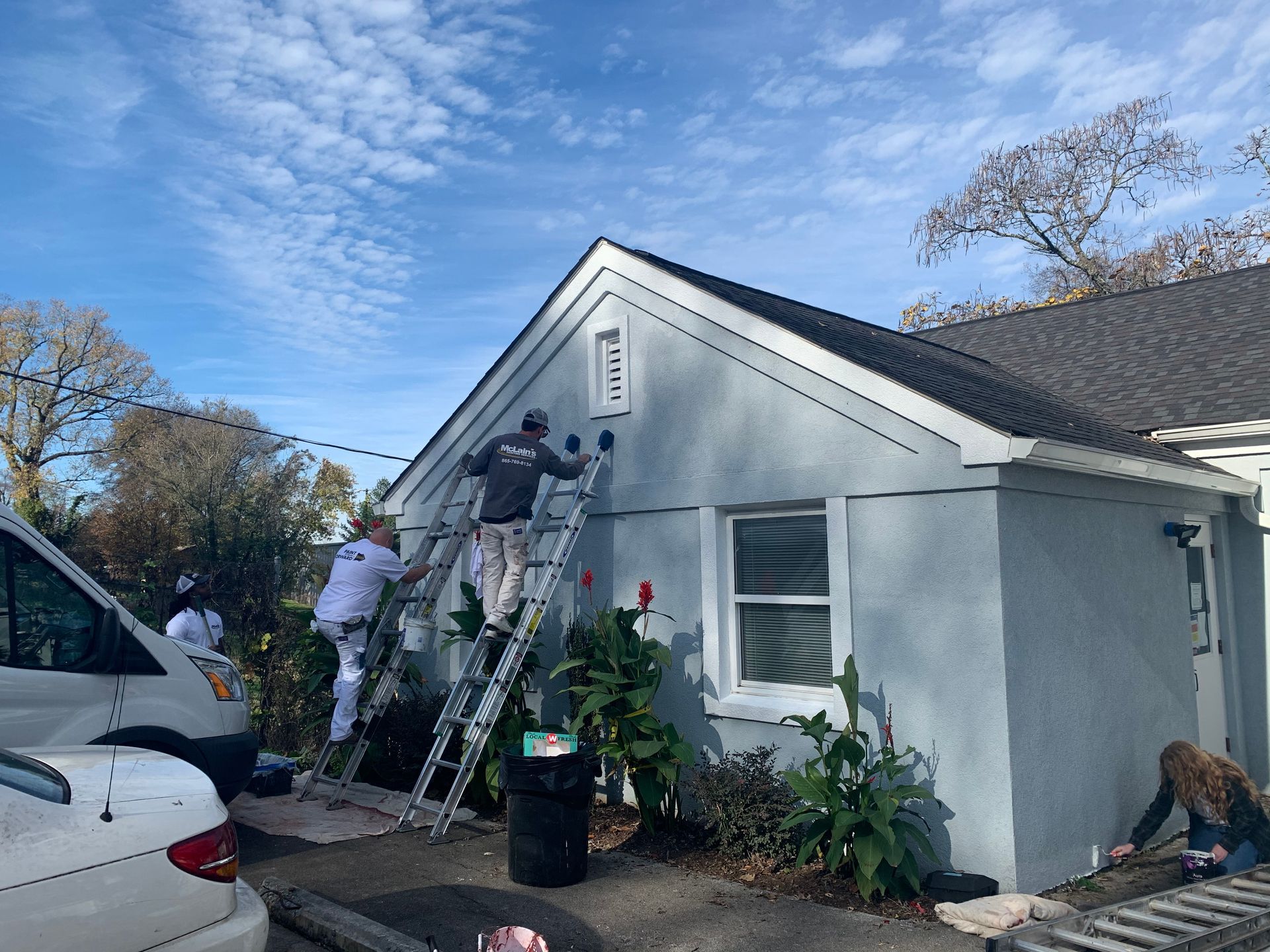 A group of people are painting the side of a house.