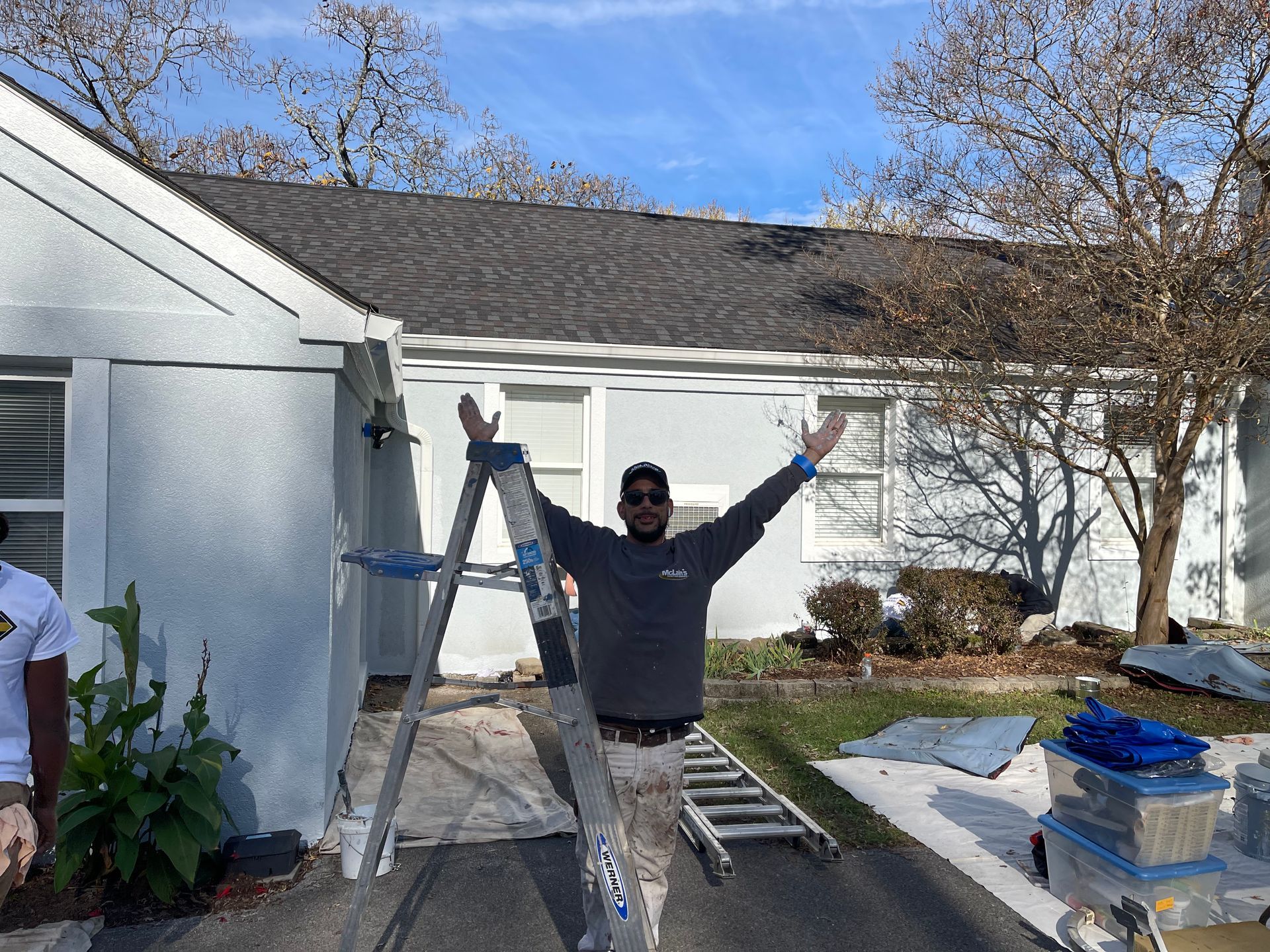 A man is standing on a ladder in front of a house.
