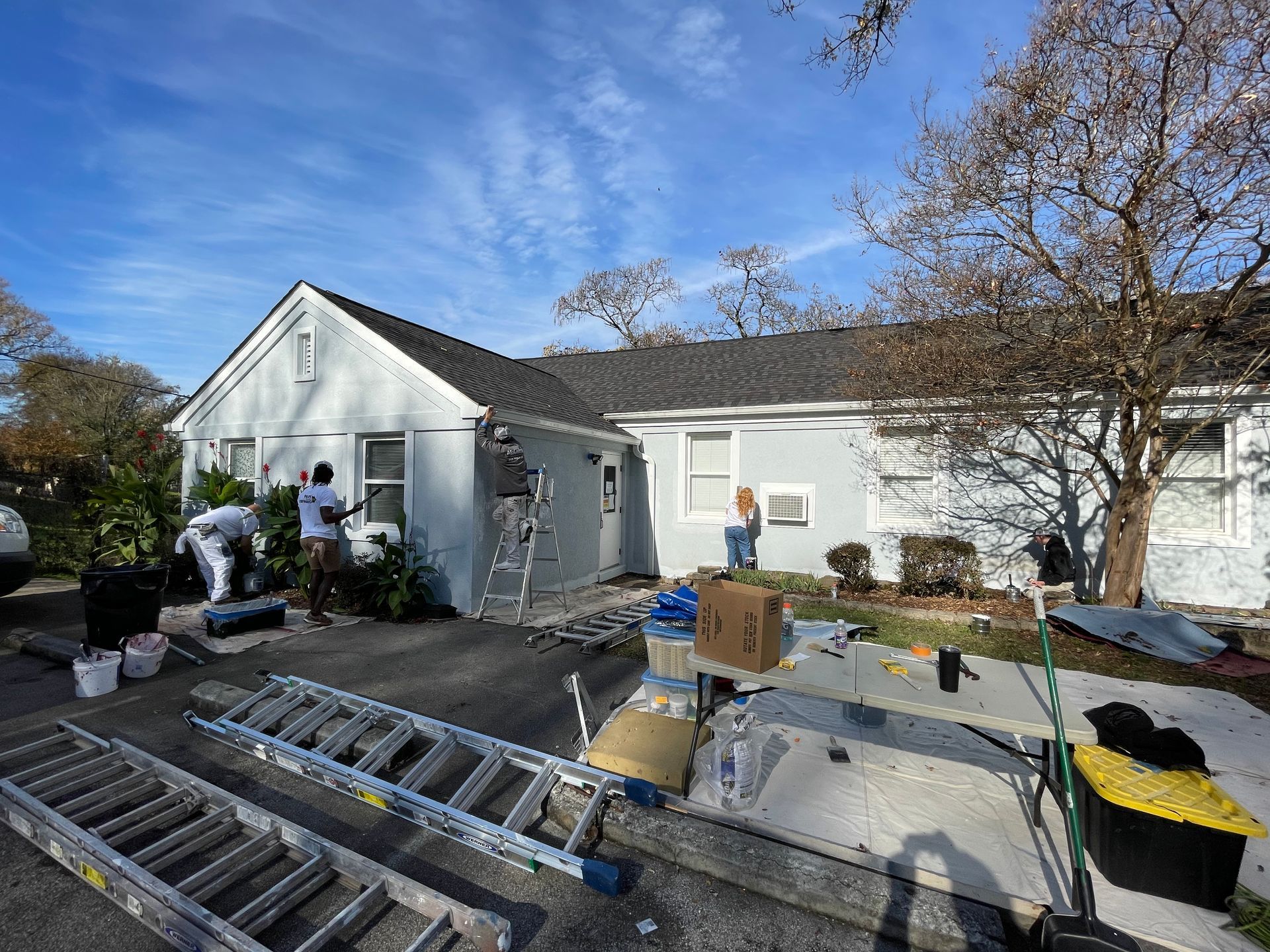A group of people are painting a white house.
