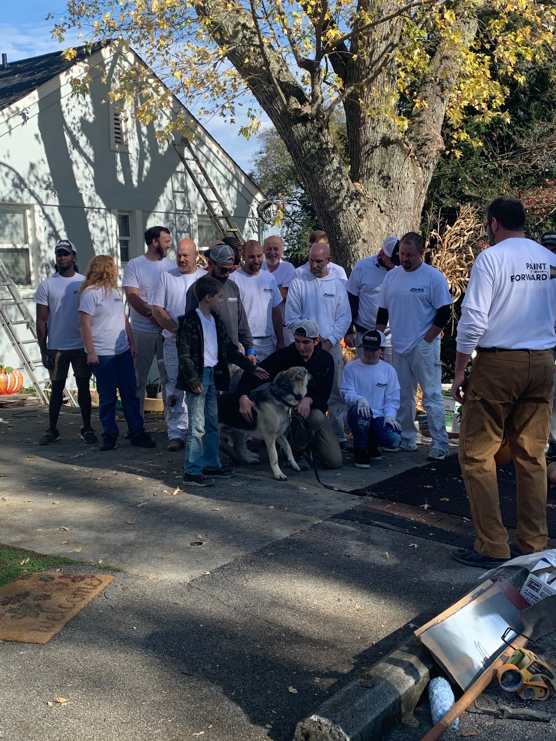 A group of people standing in front of a house with a dog.